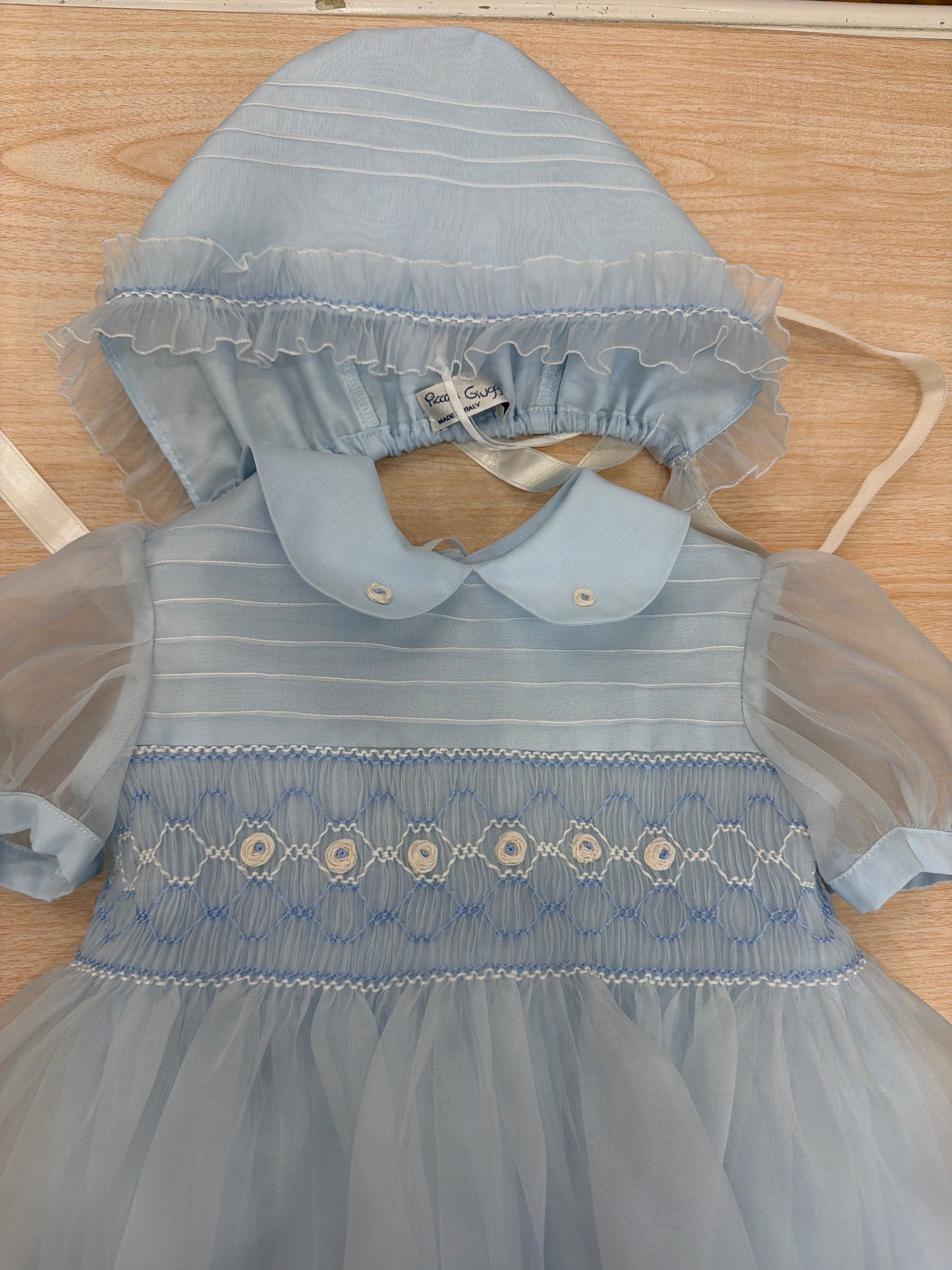 Abito Piccola Giuggiola in organza in seta celeste mezza manica con lavorazione di punto smock e lavorazione di fiori con cuffietta abbinata