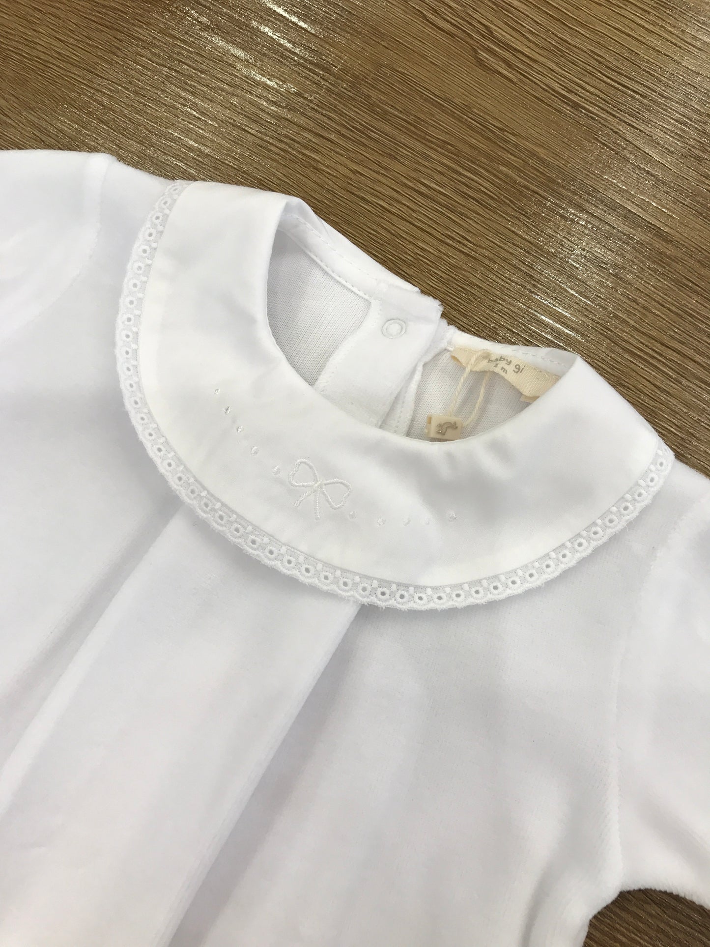 Tutina Baby Gi in ciniglia bianca intera con collo tondo smerlato bianco e fiocchetto bianco ricamato