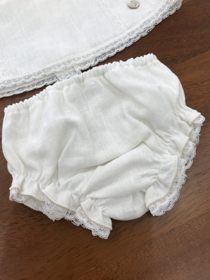 Completo Paz Rodriguez in lino bianco con fiocchi sulle spalle con merletto con fiori ricamati sul davanti con culotte e cuffia abbinata