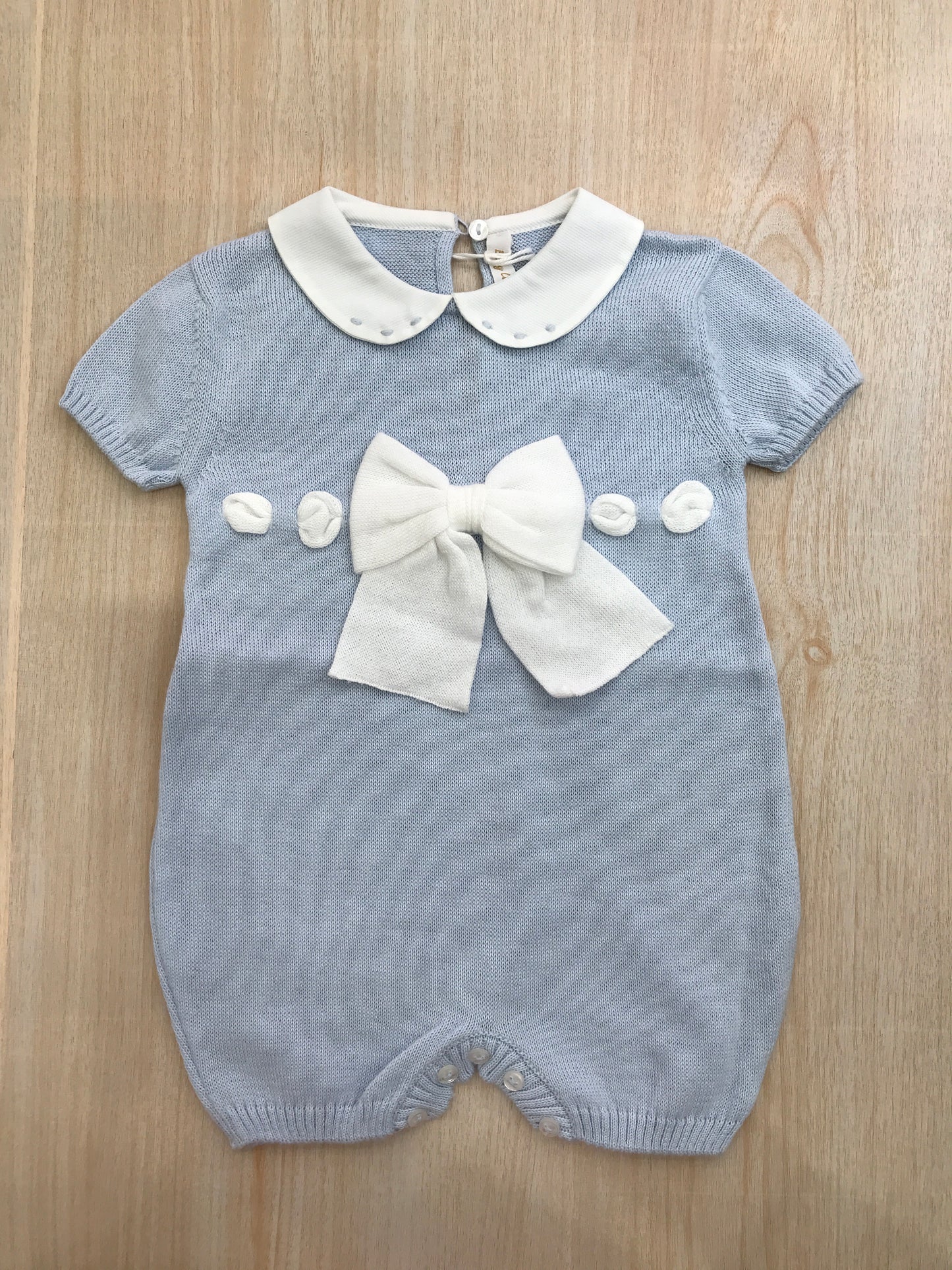 Pagliaccetto Baby Lord in filo celeste con fiocco bianco sul davanti e collo tondo bianco con pois celesti