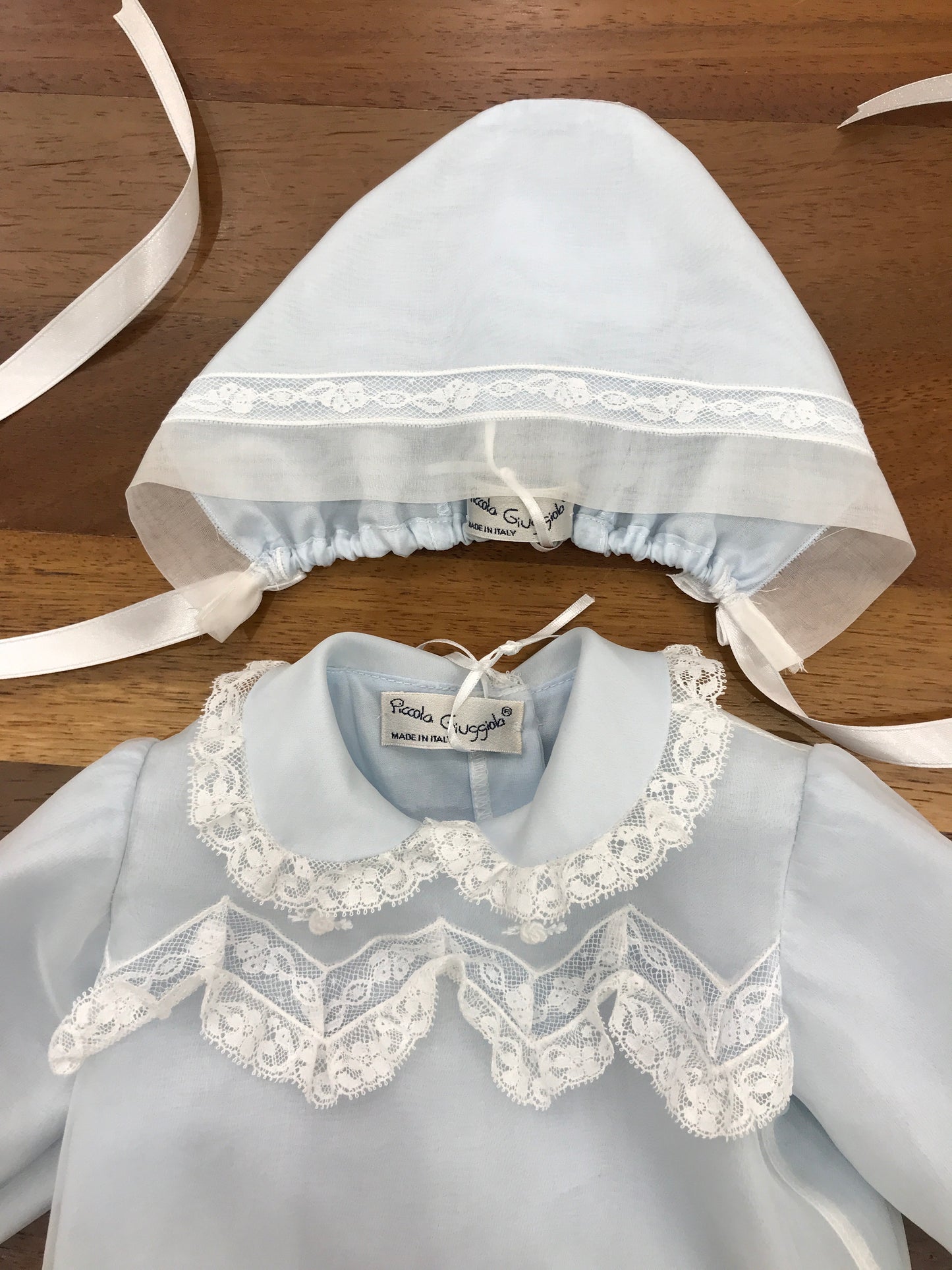Completo Piccola Giuggiola in organza celeste manica lunga lavorazione in pizzo con e roselline ricamate tutto coordinato ad una cuffia e babbucce