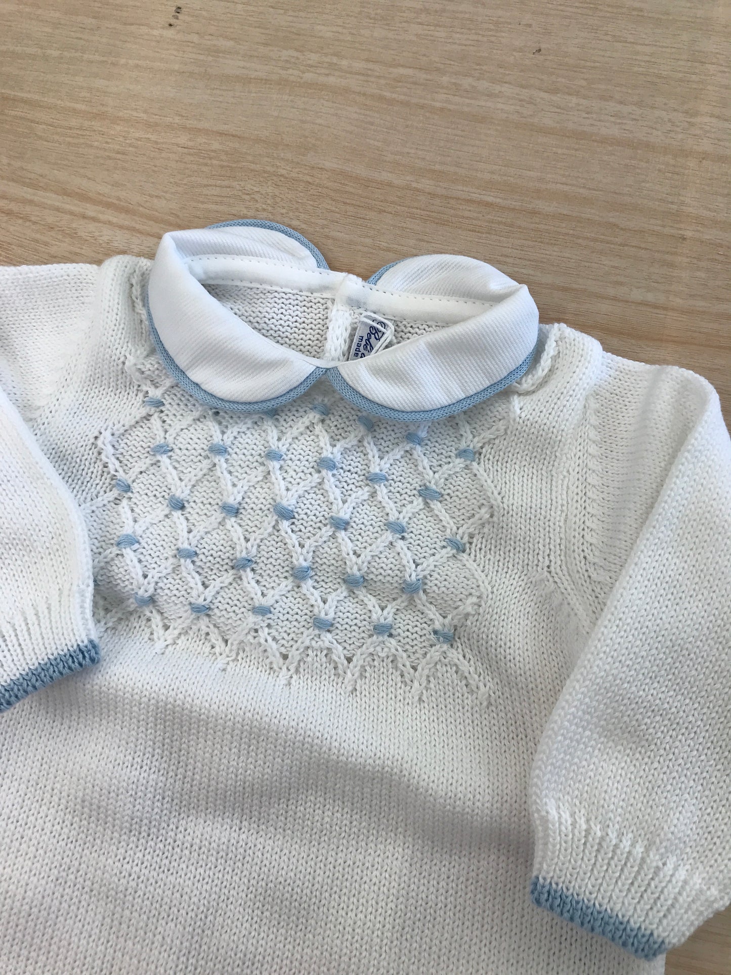 Tutina Bebè di Almy in filo bianco con rifiniture celesti con lavorazione id punto smock sul corpetto