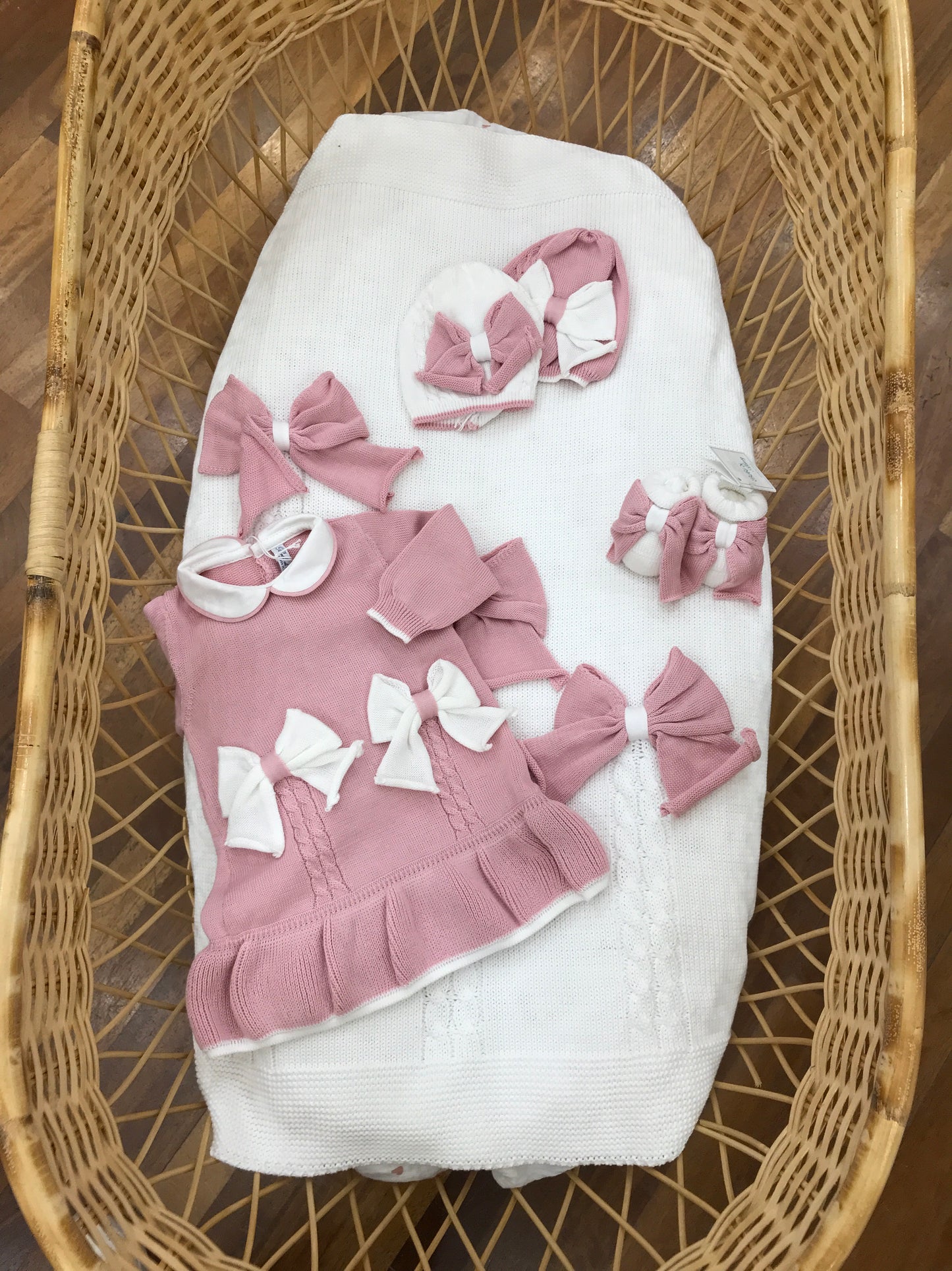Coordinato nascita Bebè di Almy in filo coperta bianca con fiocchi rosa abitino rosa con fiocchi e lavorazione di trecce abbinati cappello e babbucce