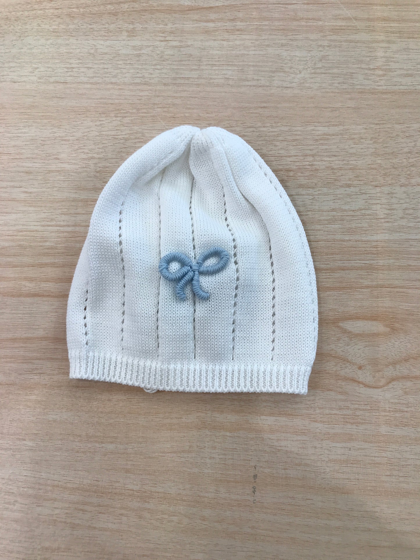 Cappello Bebè di Almy in filo bianco con fiocchetto celeste ricamato sul davanti