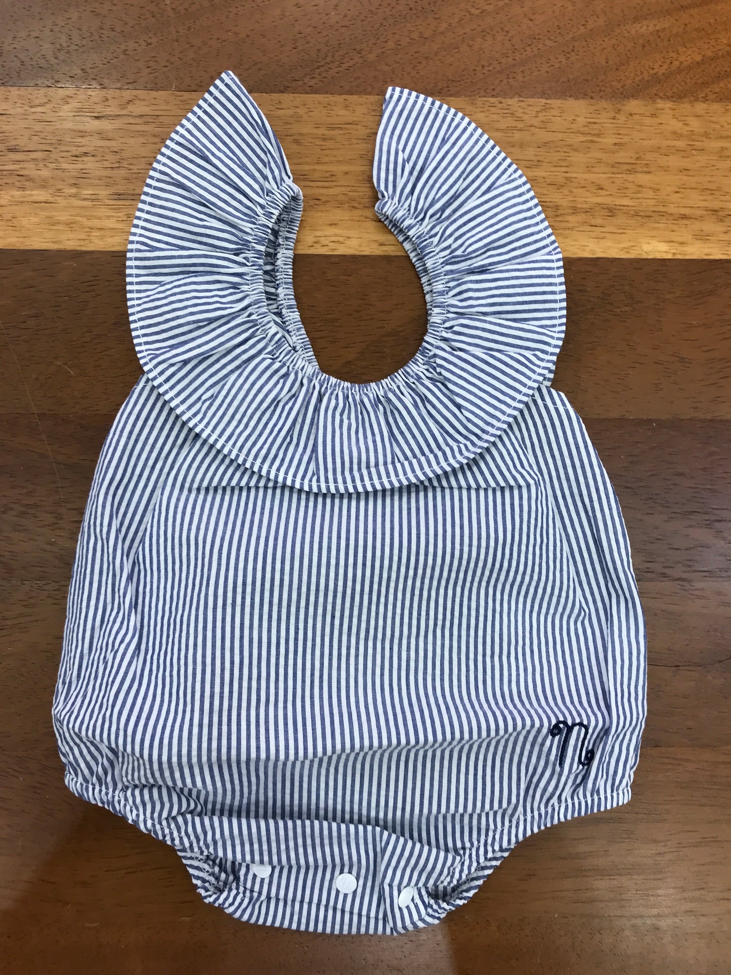 Pagliaccetto Nanan in cotone bianco e blu a righe smanicato con fiocco blu sul retro