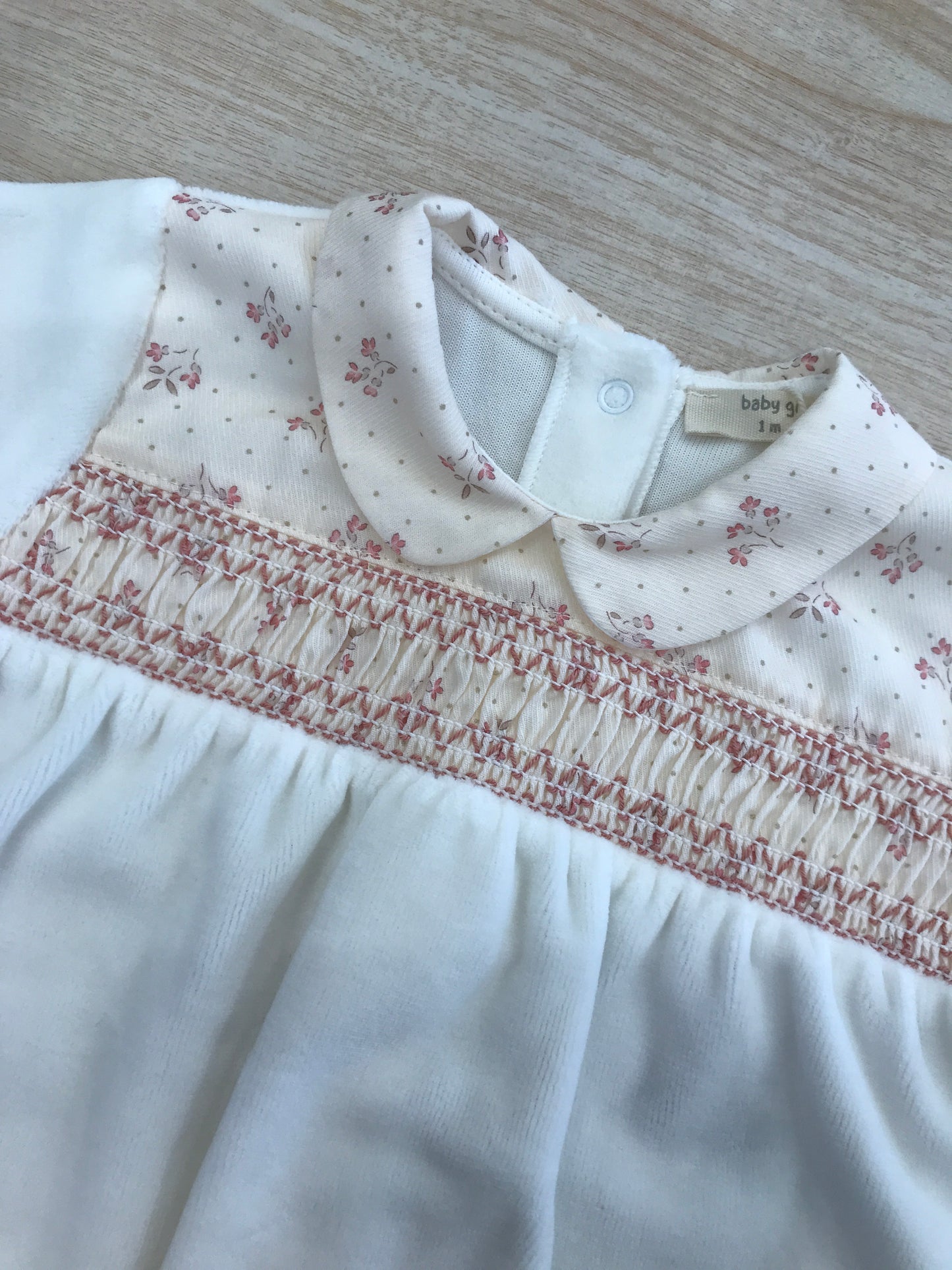 Tutina Baby Gi in ciniglia panna con lavorazione di punto smock e fiorellini sul corpetto