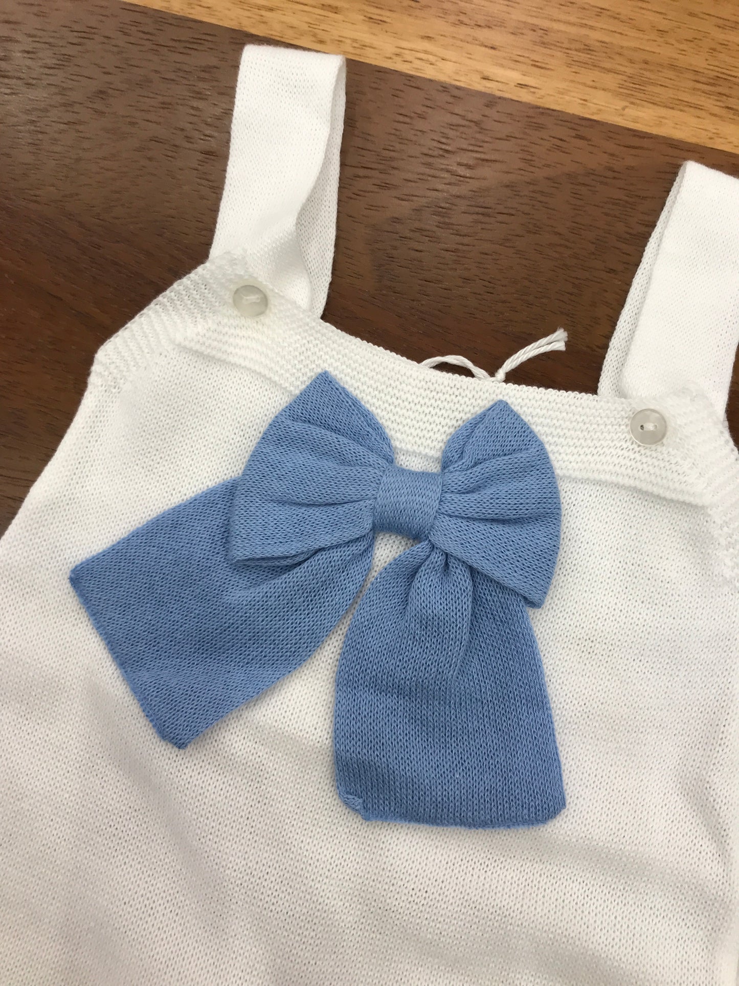 Salopette Baby Lord in filo bianco on bretelle con fiocco applicato sul petto in celeste