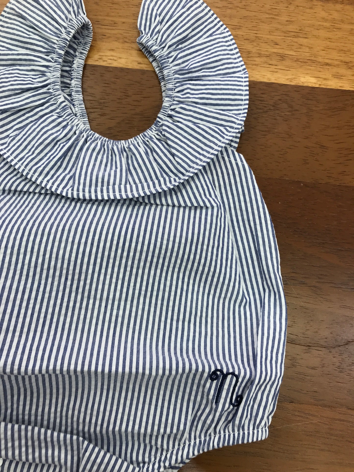 Pagliaccetto Nanan in cotone bianco e blu a righe smanicato con fiocco blu sul retro