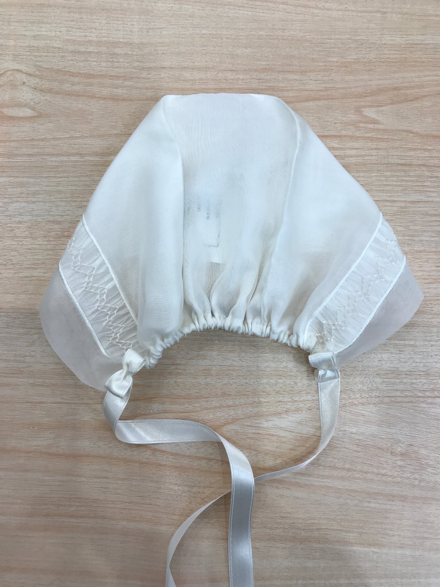 Cuffia Piccola Giuggiola in organza panna con lavorazione di punto smock sul davanti